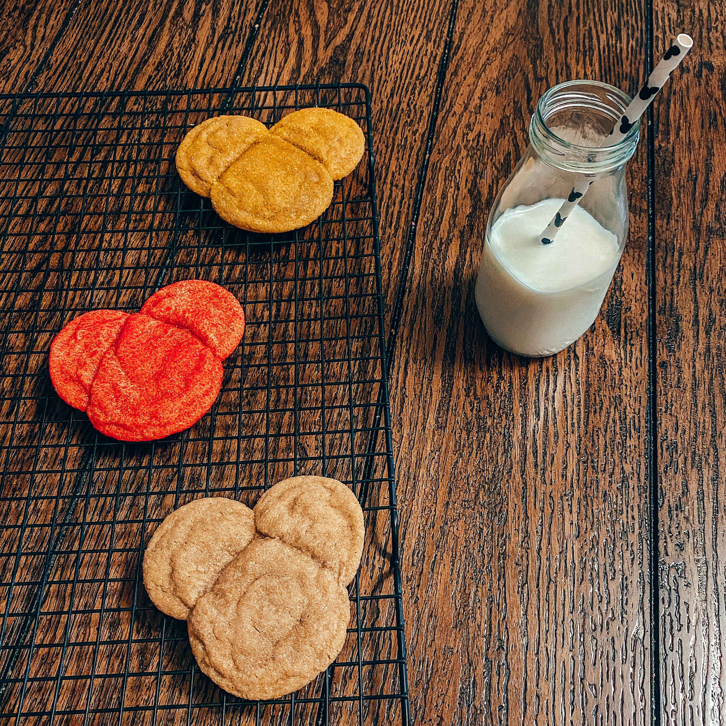 Colored mickey shaped cookies with a glass of milk