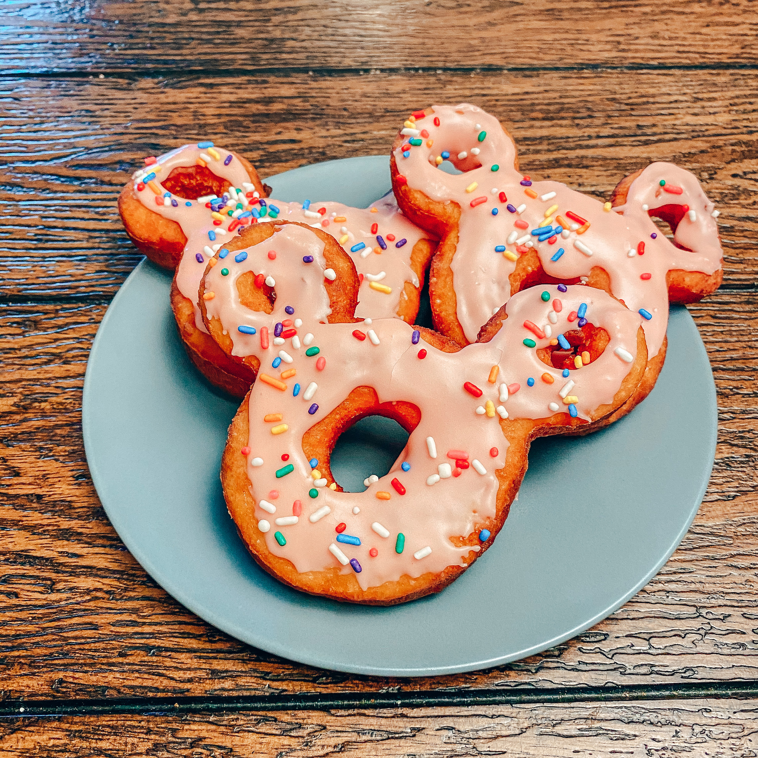 three mickey donuts on a plate