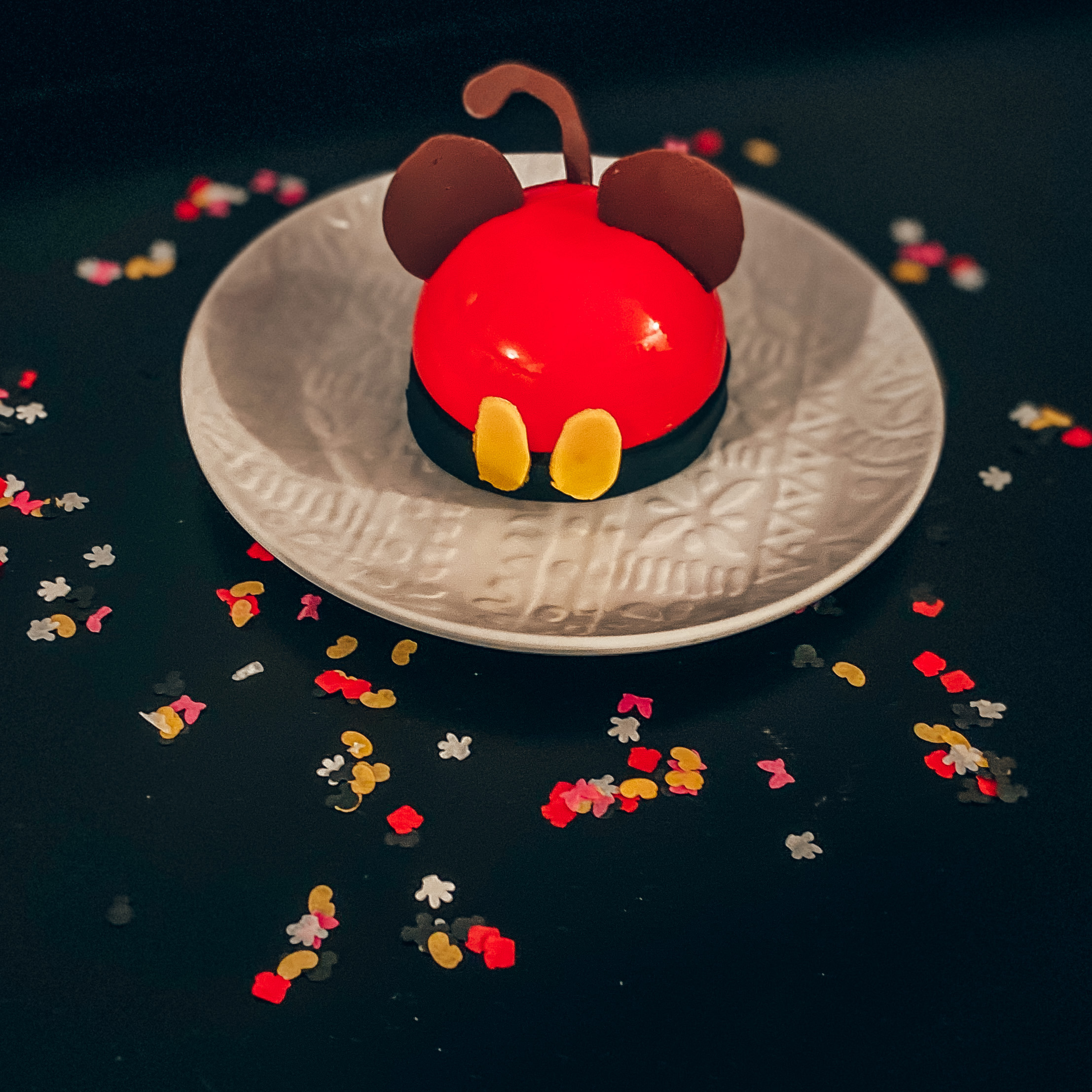 mickey mousse cake on a black background with confetti