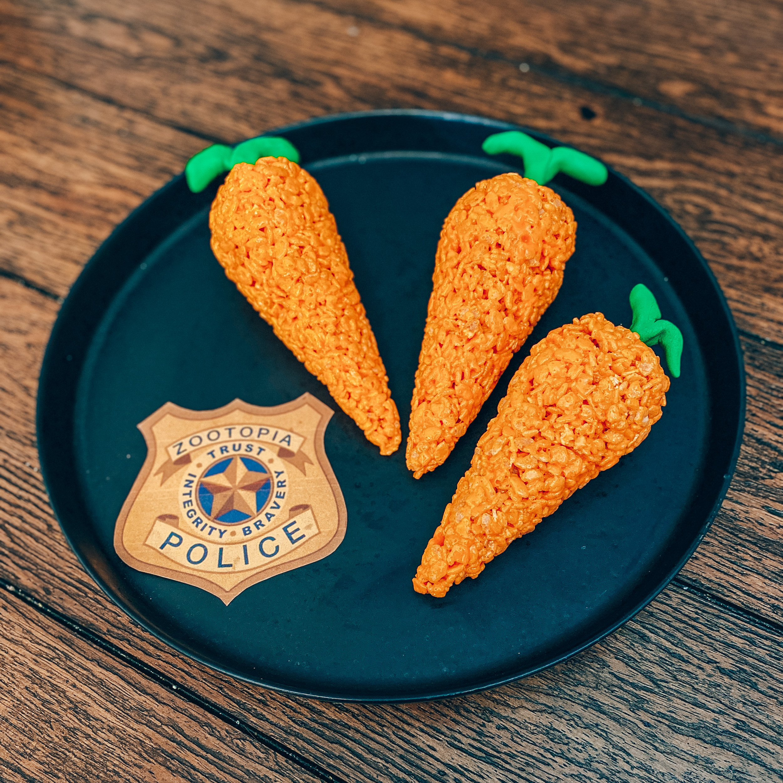 three carrot rice krispies on a platter with a Zootopia police badge