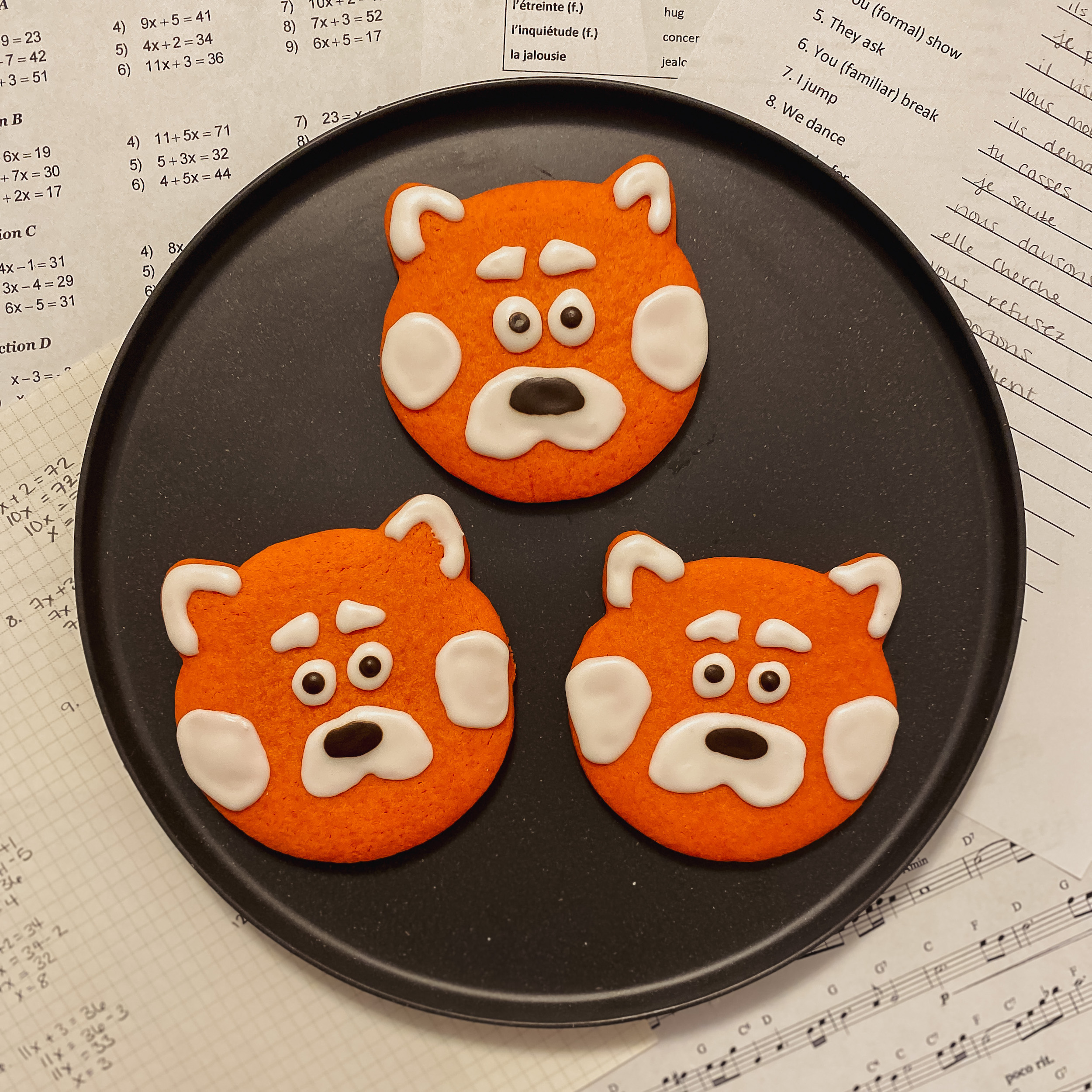 Three Mei's Panda Cookies, red panda shaped cookies with royal icing, on a plate