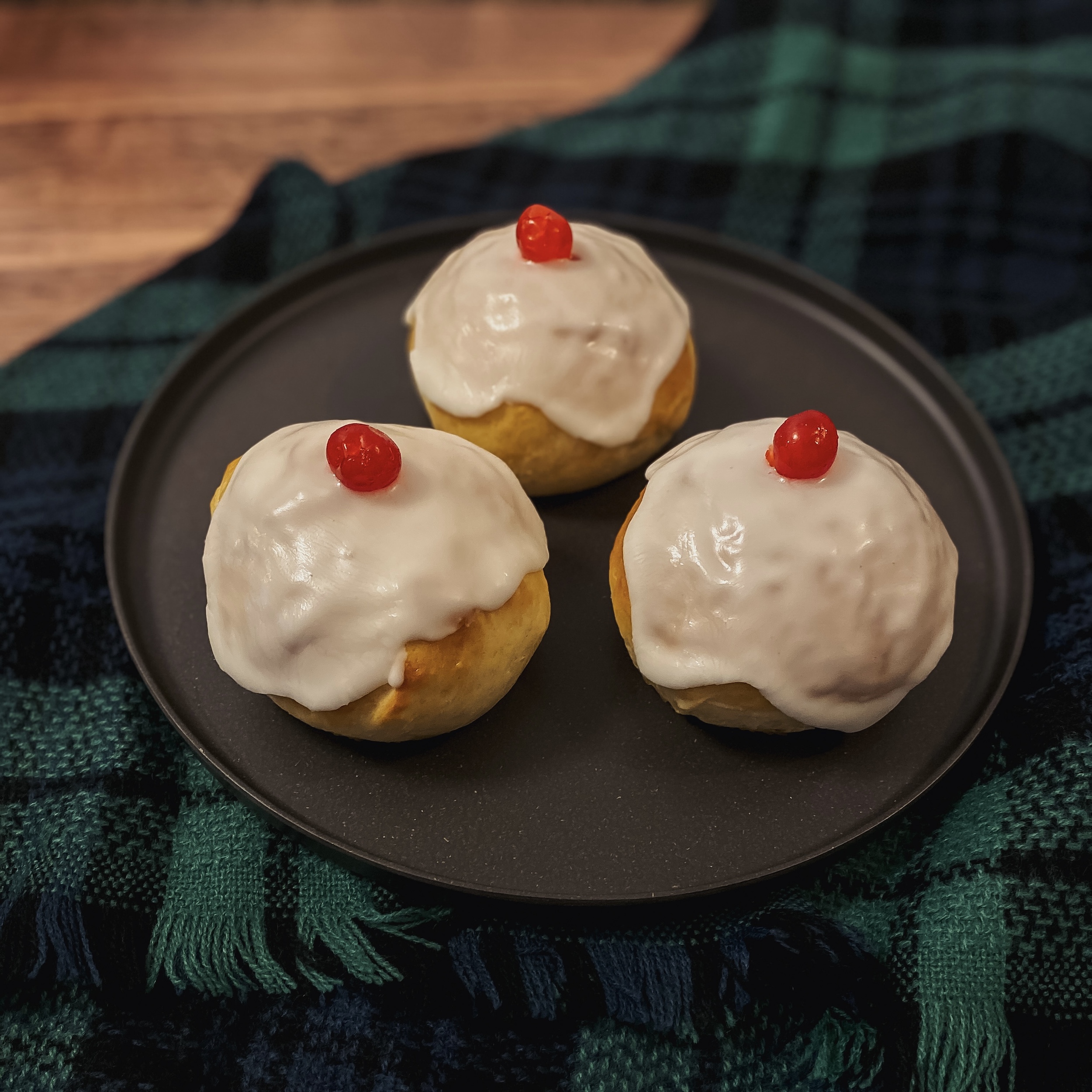 Brave Iced Buns (3 yeast buns with white icing and candied cherries) on a plate