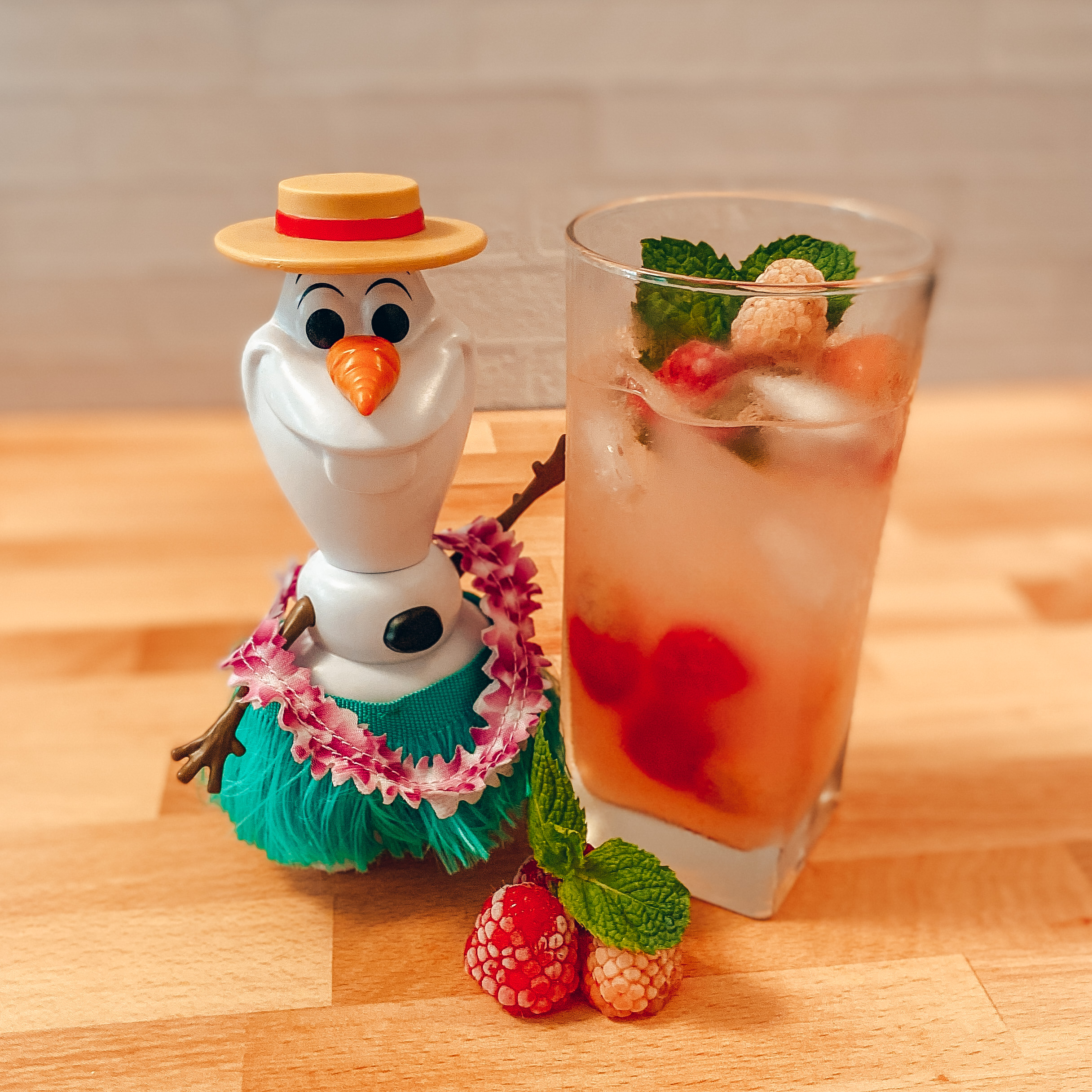 Olaf's Summertime Sip (tall glass of lemonade with frozen raspberries and a spring of fresh mint) with a plastic toy Olaf