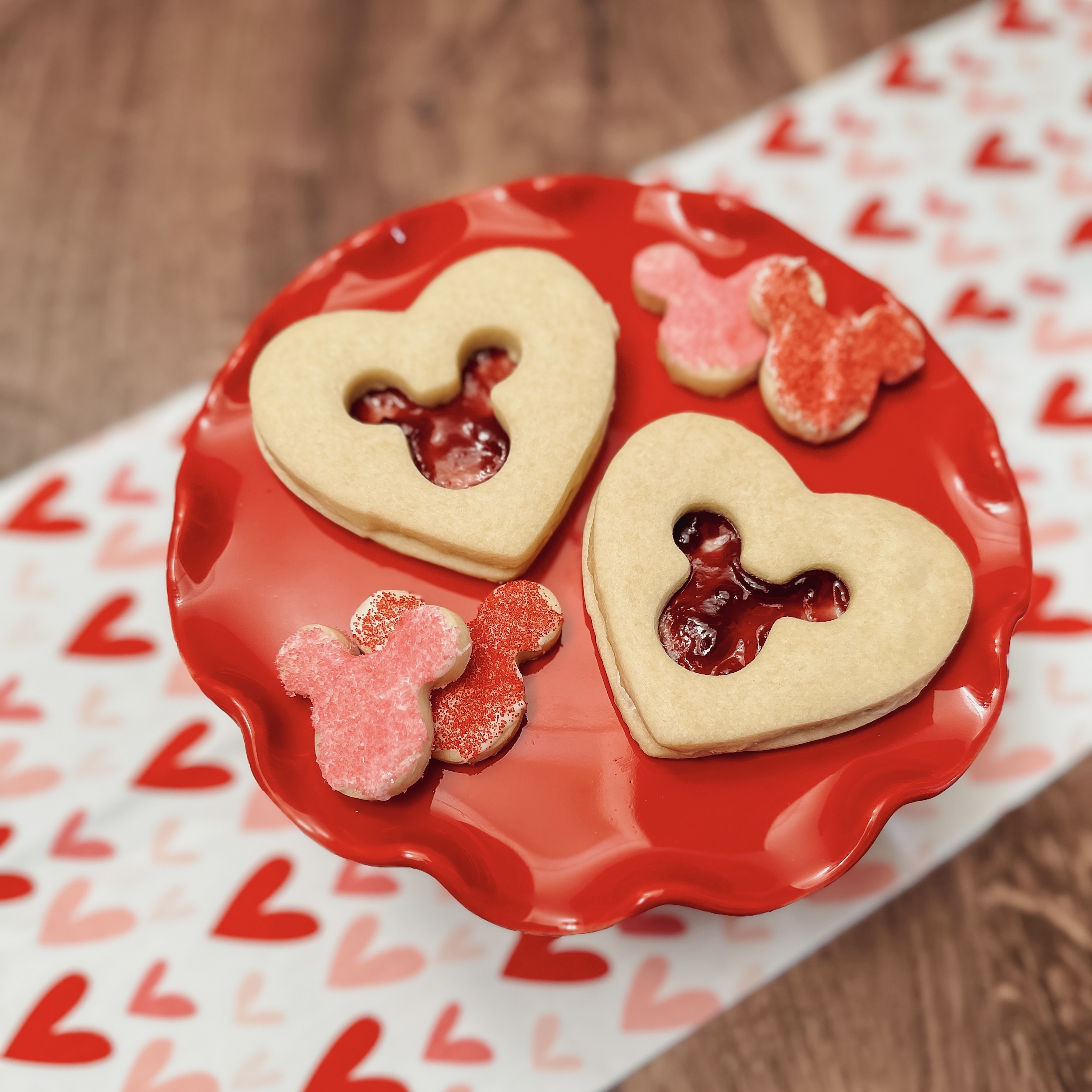Mickey's Valentine Cookies (two heart shaped shortbread cookie sandwiches with mickey shaped cut out on a red platter)